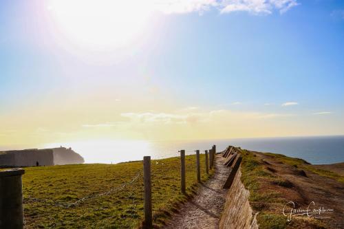 a fence on a hill next to the ocean at 10minDriveCliffsOfMoher-Cozy2Br-Parking-WiFi in Lahinch