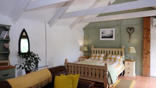 a bedroom with a bed and a couch at Cowshed Cottage located nr Kynance cove in Lizard