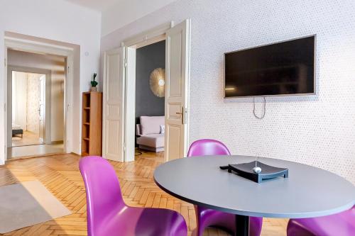 een woonkamer met een tafel en paarse stoelen bij Modern apartment 10 minutes from Old Town! in Praag