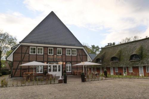 a building with a pointed roof with tables and umbrellas at Hotel Hof Holm in Brasilien