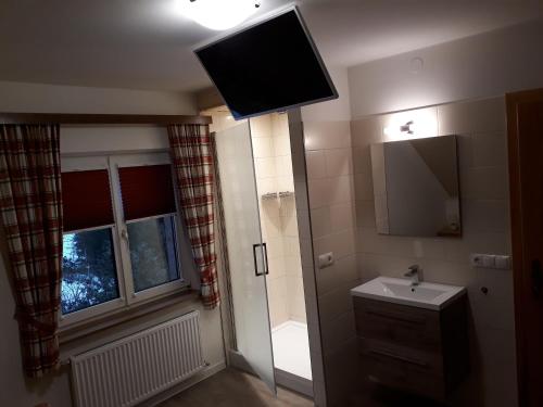 een badkamer met een wastafel en een televisie aan het plafond bij Ferienhaus Aloisia in Sankt Michael im Lungau