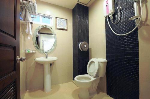 a bathroom with a toilet and a sink and a mirror at Royal Express Inn in Bangkok