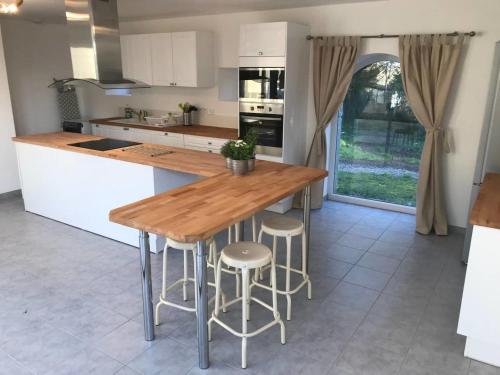- une cuisine avec une table en bois et des tabourets de bar dans l'établissement Sleeps14-PetsOK-PeacefulCountryside-YogaStudio, à Feugères