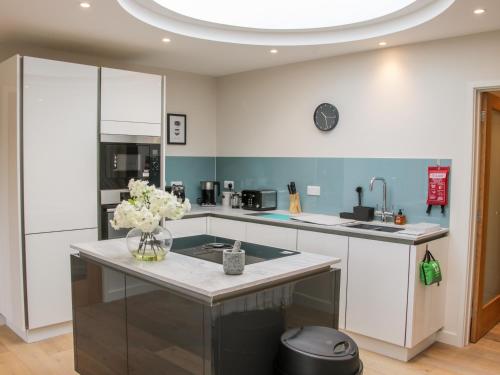 a kitchen with white cabinets and a vase of flowers at Round House in Church Stretton
