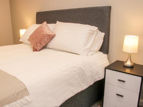 a bed with white pillows and a lamp on a night stand at Round House in Church Stretton