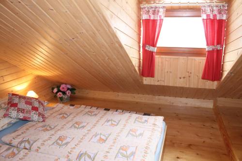 a bedroom with a bed and a window with red curtains at Drevenica Trnovec in Liptovský Trnovec