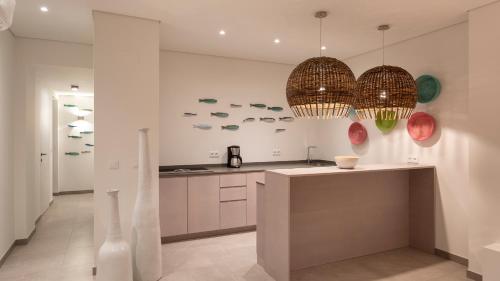 a kitchen with two chandeliers and a counter top at Vila Marina by Sevencollection in Salema