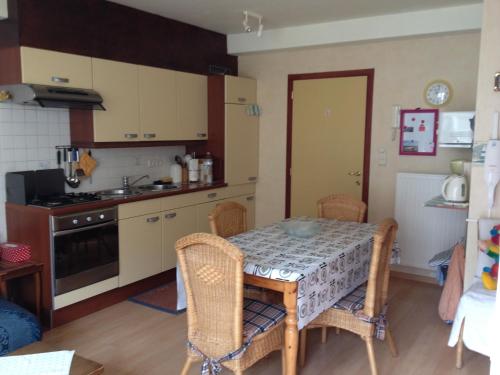 a kitchen with a table and chairs and a kitchen with a stove at Knus appartement met zijdelings zeezicht in Ostend