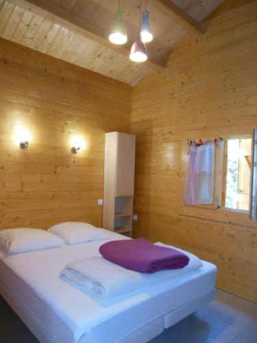 a bedroom with a white bed in a wooden room at Gîtes Bon Air in Saint-Flour