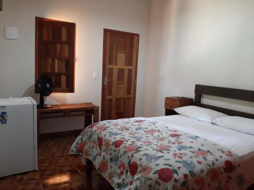 a bedroom with a bed with a floral comforter at Pousada Camping das Aguas in Pirenópolis