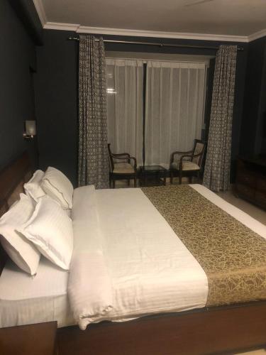 a bedroom with a bed with two chairs and a window at Aloha Apartments by blissful Ganges in Rishīkesh
