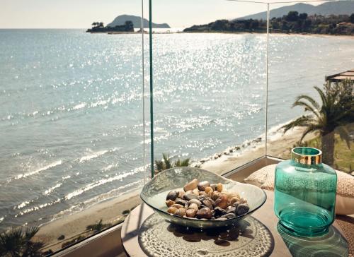 eine Schüssel Steine auf einem Tisch neben einem Fenster mit Meerblick in der Unterkunft Shellona Rooms & Apartments in Zakynthos