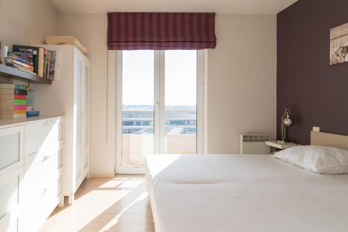 una camera con un letto bianco e una grande finestra di Zongericht appartement met zicht op de jachthaven a Ostenda