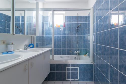bagno con piastrelle blu, lavandino e vasca di Zongericht appartement met zicht op de jachthaven a Ostenda
