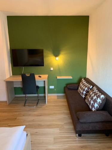 a living room with a couch and a desk with a television at Steimke's Landhotel in Graue