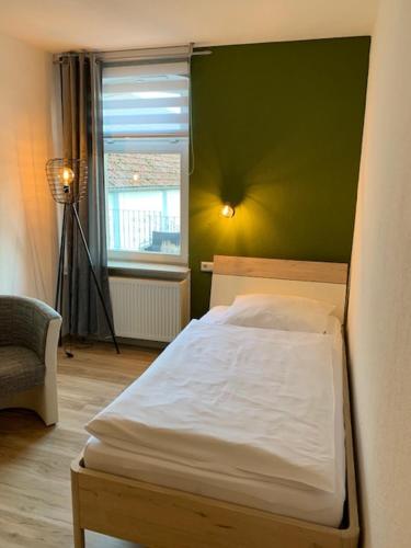 a bedroom with a white bed and a green wall at Steimke's Landhotel in Graue