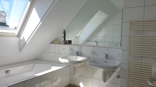 a white bathroom with two sinks and a window at Somnar Panoramaloft mit Hästens Betten - Rheinblick 150qm in Neuss