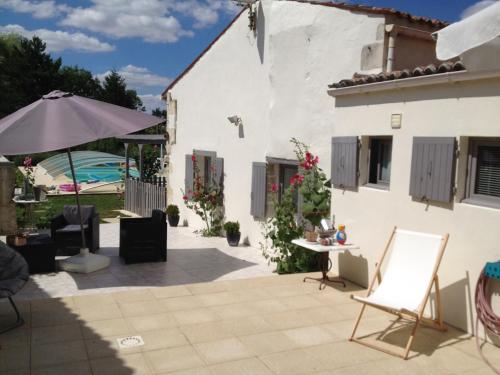 un patio con una casa blanca y una sombrilla en Studio avec piscine privee jardin clos et wifi a Saint Jean d'Angely, en Saint-Jean-dʼAngély