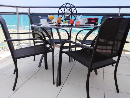 ein Tisch mit einem Teller Essen auf einem Balkon in der Unterkunft Appartement spacieux à Canet-en-Roussillon 122m² avec vue sur la mer in Canet-en-Roussillon