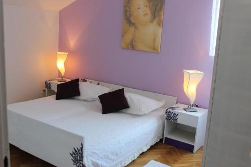 a bedroom with a bed with two lamps on it at Apartments Petrada in Omiš