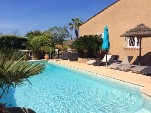 une piscine avec des chaises et un parasol dans l'établissement Villa avec Piscine Privée à Carqueiranne, à Carqueiranne