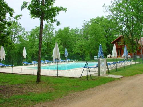 a swimming pool with umbrellas and umbrellas at Maison de 2 chambres avec vue sur le lac piscine partagee et jardin amenage a Lachapelle Auzac in Lachapelle-Auzac