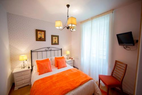 Rua De Francos的住宿－3 bedrooms house with balcony at Teo，一间卧室配有带橙色枕头的床和电视。