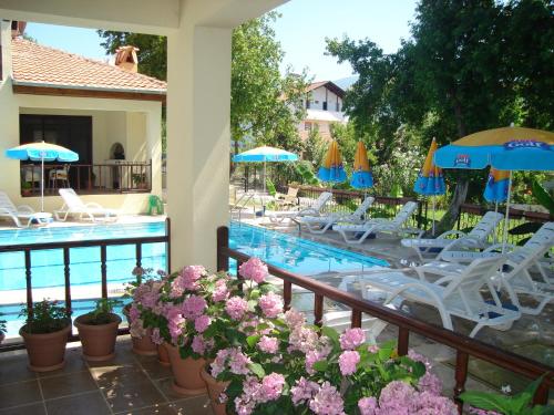 balcón con piscina, sillas y sombrillas en Begonville Villa, en Koycegiz