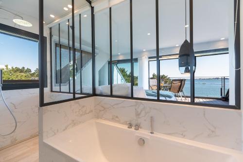 bañera en una habitación con ventanas grandes en La Villa du Guern, en Baden