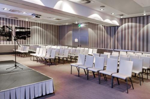 a conference room with white chairs and a stage at Holiday Inn Bydgoszcz, an IHG Hotel in Bydgoszcz