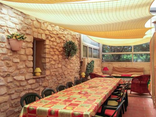 Cette chambre est dotée d'une table, de chaises et d'un mur en pierre. dans l'établissement Villa spacieuse à Vaison-la-Romaine avec piscine privée, à Vaison-la-Romaine