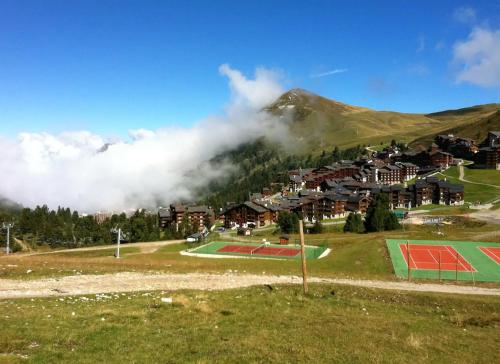 un village dans les montagnes avec un court de tennis dans l'établissement Studio cosy à Mâcot-la-Plagne 24 m² avec vue montagne, à Mâcot La Plagne