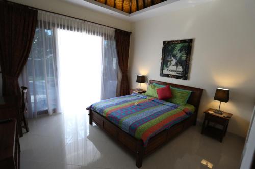 a bedroom with a bed and a large window at Villa Barong in Candidasa