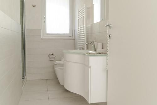 a white bathroom with a sink and a toilet at Yachting Residence in Lavena Ponte Tresa