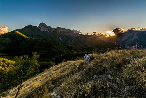 a view of a mountain range with the sun setting at Cozy House in Castelnuovo di Garfagnana + Large Garden in Castelnuovo di Garfagnana