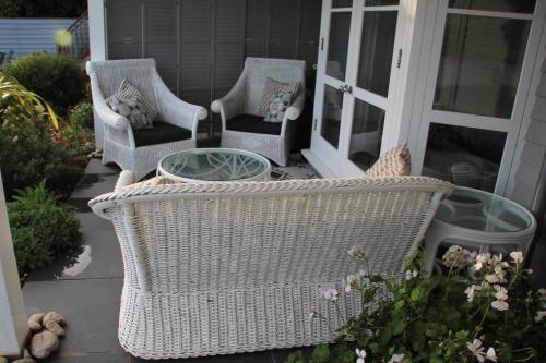 two wicker chairs and a glass table on a porch at Compass Rose in Dartmouth
