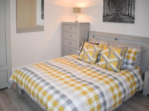 - une chambre dotée d'un lit avec une couverture en damier jaune et blanc dans l'établissement Rose Cottage Captivating 1-Bed Cottage in Bangor, à Bangor