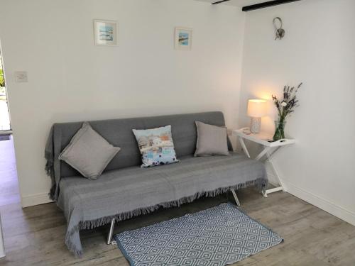 a gray couch in a living room with a table at Captivating Isolde Cottage with pool near St Ives in Camborne
