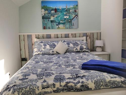 a bedroom with a bed with a blue and white comforter at Captivating Isolde Cottage with pool near St Ives in Camborne