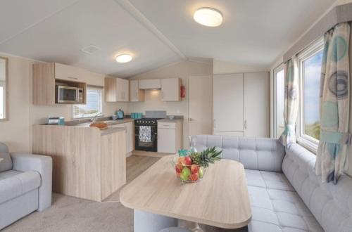a kitchen and living room with a table and a couch at Stunning 6 Birth Caravan in Skegness Herons Mead in Orby