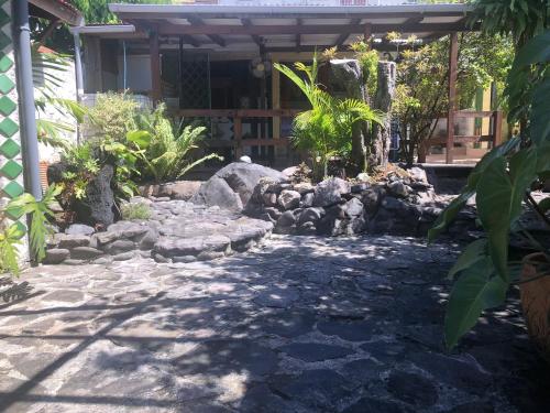 un jardín con una pasarela de piedra frente a una casa en Studio avec jardin clos et wifi a Basse Terre, en Basse-Terre