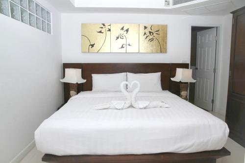 una camera da letto con un letto bianco con due cigni sopra di 2 bedrooms appartement with sea view shared pool and furnished balcony at Phuket 2 km away from the beach a Phuket