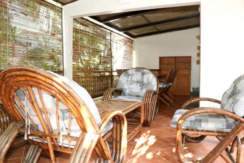 a porch with wicker chairs and a wooden table at Cosy House in Blue Bay with Private Parking and Terrace in Blue Bay