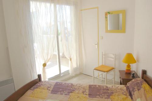 a bedroom with a bed and a window and a chair at Appartement cosy à Valras-Plage / 48m² / Piscine partagée in Valras-Plage