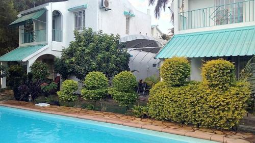a house and a swimming pool in front of a house at Spacious House in Flic en Flac with Shared Pool in Flic-en-Flac
