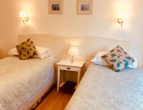 a bedroom with two beds and a table with a lamp at Hazelbrook Self Catering - Maximum 6 persons in Westport