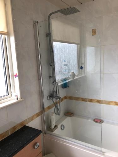 a bathroom with a shower with a white tub at Limegrove Comfortable three bedroom house in Law