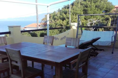 a wooden table and chairs on a patio at 3 bedrooms villa at Magomadas 10 m away from the beach with sea view terrace and wifi in Magomadas