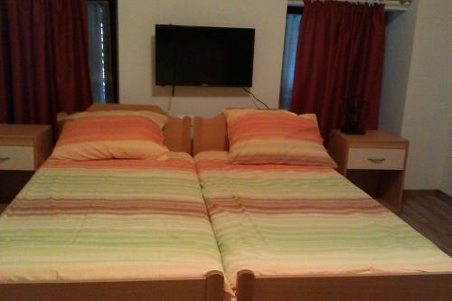 a bed with two pillows and a television in a bedroom at Studio Brnat in Kobarid