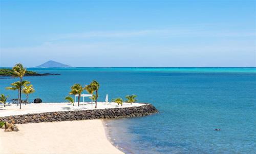 a beach with palm trees and the ocean at Modern Apartment in Pereybere + Pool in Pereybere